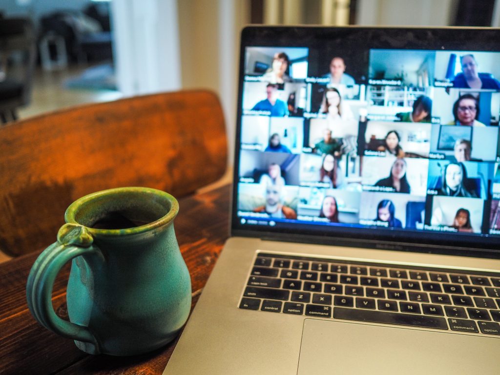 laptop and mug on table with video conference on laptop screen