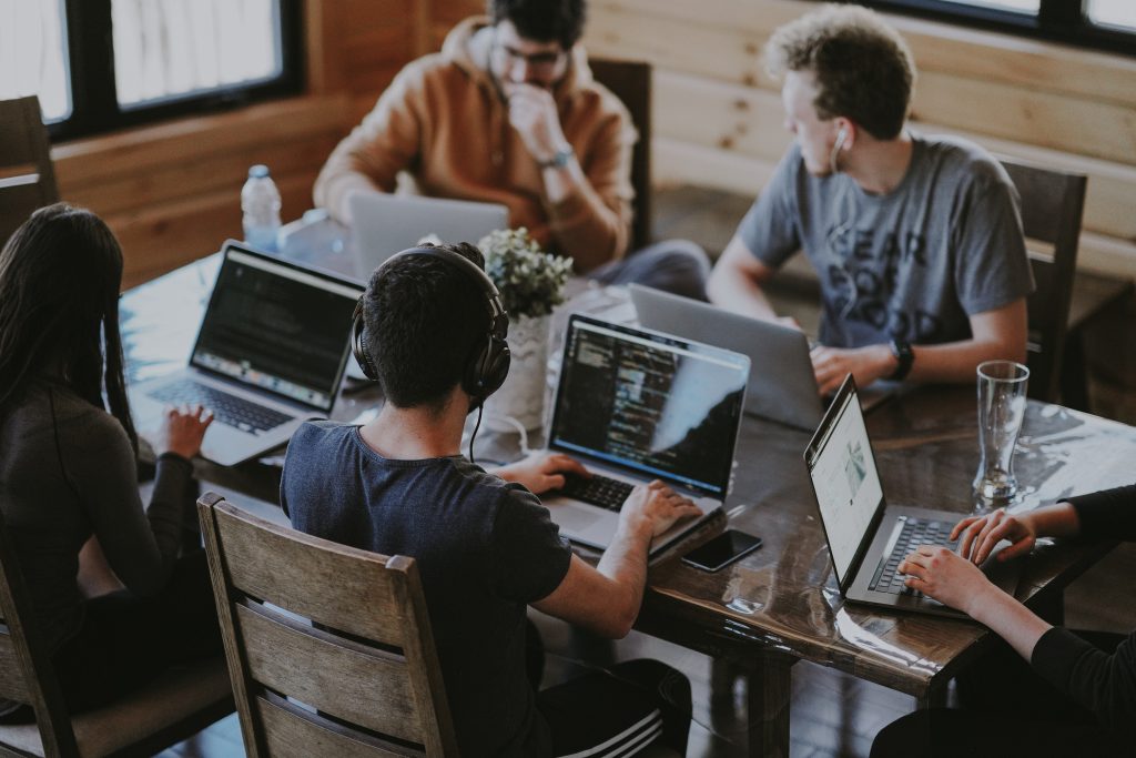 people around a wooden pub table on laptops