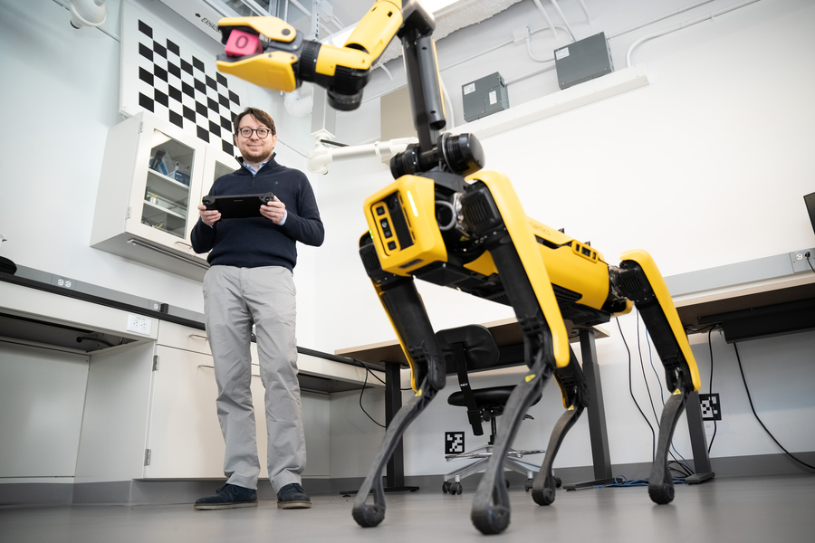 Luca Carlone stands next to a Boston Dynamics Spot robot